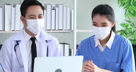 Asian man doctor and nurse in headsets working with desktop computer at hospital. customer service agents. Specialist of health care and medical consultant concept.