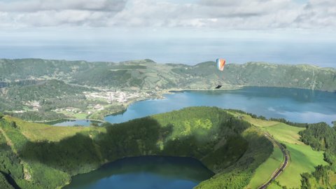 Drone shot of paraglider with parachute paragliding over Lagoon of Seven Cities at Miradouro do Cerrado das Freiras, Sao Miguel island, Azores, Portugal, Europe. Parachutist flying in sky, 4k footage