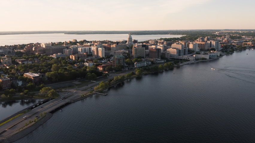 Flying above Lake Monona towards downtown of Madison with domed Wisconsin State Capitol on horizon, sunset light