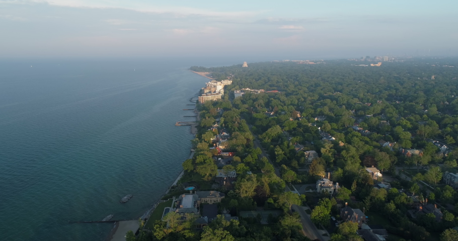 Aerial above Lake Michigan and  Chicago North Shore suburbs with houses among green trees, United States