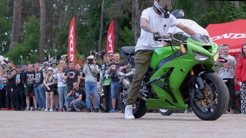 UKRAINE, CHERKASY, JUNE 04, 2021: Performing incredible professional motorcycle stunts. Stuntman rides rear wheel past a crowd of people. Moto festival. Spectacular biker show. Zoom. Slow motion.