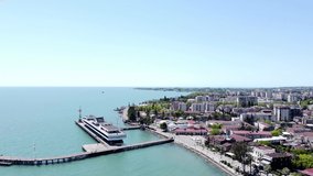 Summer aerial video filming from a drone in sunny Abkhazia. View of the city of Sukhumi and the Black Sea, as well as a seaport. Translation of the inscription on the building: 