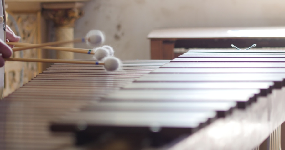 Close up shot of professional male musician hands playing xylophone marimba. white sticks playing on the instrument, man fast drumming traditional classical music on impressive musical instrument.