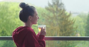 Woman drinks tea a cup, and relax on terrace at home in autumn rainy day. Health care, authenticity, sense of balance and calmness. Work from home. 4K Video
