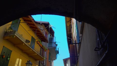Wonderful panoramas of the narrow streets of a small European Italian-Swiss town near Lake Como. colored houses. Video in motion. Blue sky. Ancient houses and streets. Flag. ITALY, Como, June 2021 