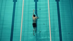 Aerial Top View: Muscular Male Swimmer Diving in Swimming Pool. Professional Athlete Gracefully Jumps, Swims Freestyle, Training Determined to Win Championship. Cinematic Slow Motion, Stylish Colors - Powered by Shutterstock - Get 15% off with code: PIKWIZARD15
