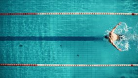 Aerial Top View: Muscular Male Swimmer in Swimming Pool. Professional Athlete Swims in Butterfly Style, Determination in Training to Win Championship. Cinematic Slow Motion, Stylish Colors - Powered by Shutterstock - Get 15% off with code: PIKWIZARD15