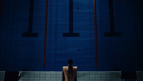 Aerial Top View Male Swimmer Jumps, Dives into Swimming Pool. Professional Athlete Winning World Championship. Dark Dramatic Saturated Colors, Cinematic Light, Artistic Top Down Flyover Slow Motion - Powered by Shutterstock - Get 15% off with code: PIKWIZARD15