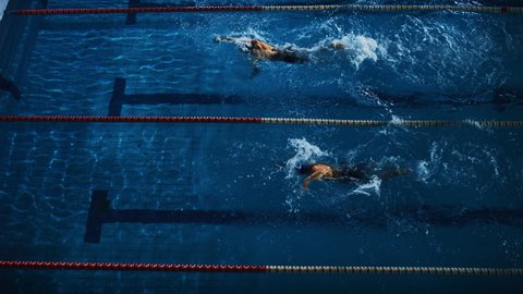 Swim Race: Two Professional Swimmers jump dive in Swimming Pool. Athletes Compete the Best Wins Championship. Slow Motion, Aerial Top View Tracking Shot. Dark Dramatic Colors, Cinematic Lap Lane Light