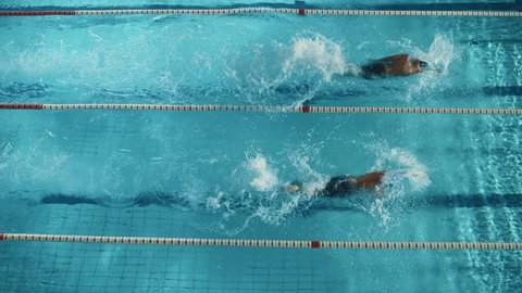 Swim Race: Two Professional Swimmers jump dive in Swimming Pool, Stronger and Faster Wins. Athletes Compete the Best Wins Championship, World Record. Slow Motion, Aerial Top View Tracking Shot