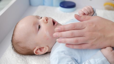 Closeup of mother applying moisturizing baby creme to prevent dry skin. Concept of hygiene, baby care and healthcare.