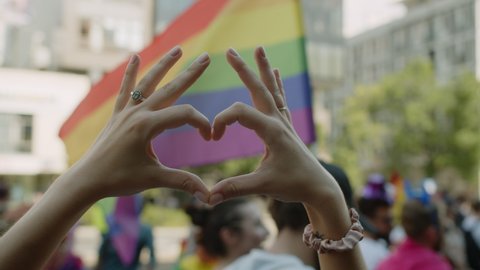 WARSAW, POLAND - JUNE 6 2021: Hands Make Heart Sign Supporting In Front Of People Walk The Streets With Rainbow Flags And Protest Signs On Pride March Celebration Event Symbol Of LGBT GLBT Love Equal