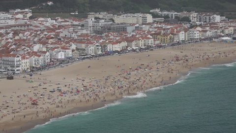 NAZARE, PORTUGAL – 12 JUNE 2021: People sunbathing at beach of Nazare in Portugal (after Covid-19 lockdown measures are eased)
