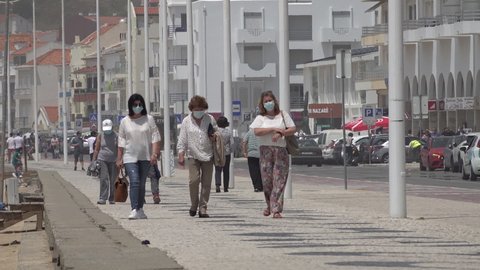 NAZARE, PORTUGAL – 12 JUNE 2021: Women wearing face masks walk along promenade in popular beach town Nazare, as Portugal eases Covid-19 lockdown measures
