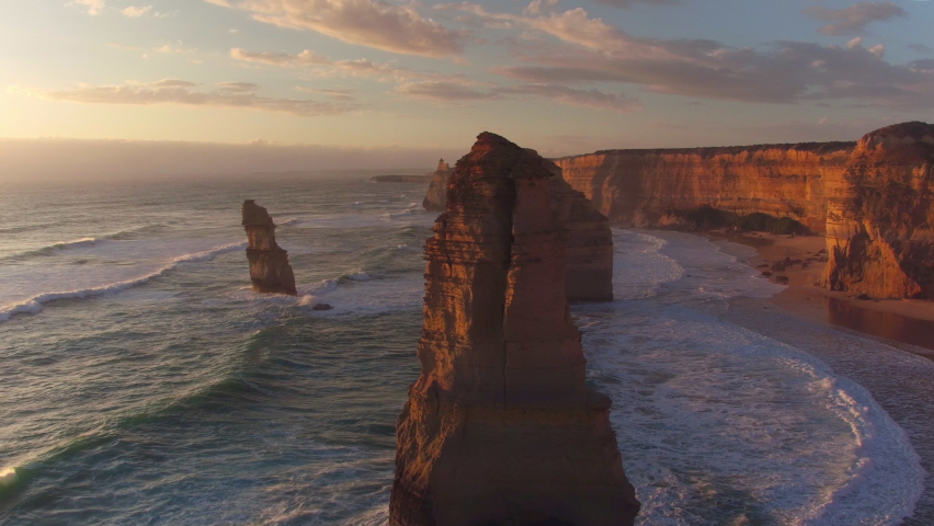 AERIAL: Spectacular drone point of view of the famous 12 Apostles beach in Australia on a sunny summer evening. Golden sunshine illuminates the cliffs and other rock formations on coast of Australia. | Shutterstock HD Video #1075123268