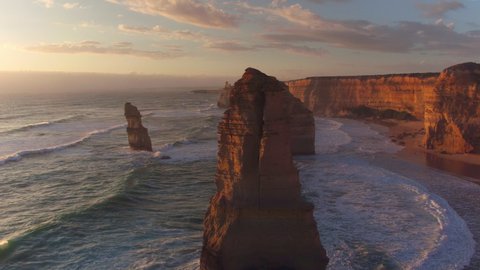 AERIAL: Spectacular drone point of view of the famous 12 Apostles beach in Australia on a sunny summer evening. Golden sunshine illuminates the cliffs and other rock formations on coast of Australia. Video Stok