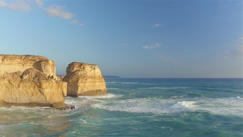 AERIAL: Flying along the 12 Apostles shore on a sunny summer day in Australia. Picturesque drone point of view of the limestone formations at the coast of Victoria. Cliffs and promontories in Oceania.