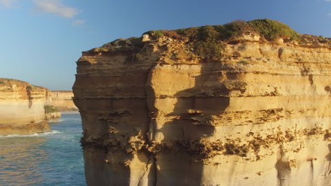 AERIAL: Flying along the spectacular limestone cliff shore in sunny Australia. Scenic drone point of view of the endless ocean and rugged rocky coastline of Victoria. Rugged Australian shoreline.