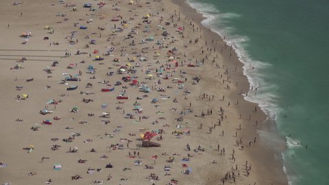 NAZARE, PORTUGAL – 12 JUNE 2021: Abstract view of people visiting the beach in Nazare town in Portugal, as the country lifts many Covid-19 restrictions towards the Summer holiday
