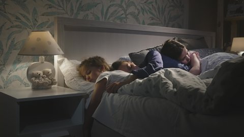 Young attractive mother sleeping with children, daughters together.