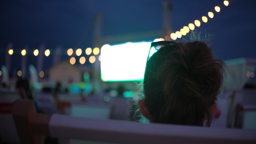 Caucasian Woman Watching Movie in Open Air Beach Cinema during Summer Film Festival Royalty-Free Stock Footage #1075135997