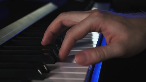 Musician plays piano during a live performance. right hand playing keys in a bluish lightning. keyboardist at a concert rocking audience. just a pianist playing piano keys notes midi digital piano