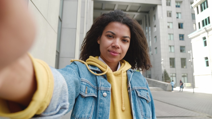 POV portrait of cheerful mixed race woman with curly hair chatting and waving hand making video call outside in city Royalty-Free Stock Footage #1075141061