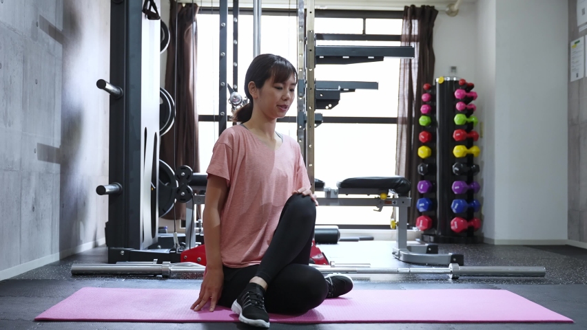 attractive asian woman stretching in the in gym