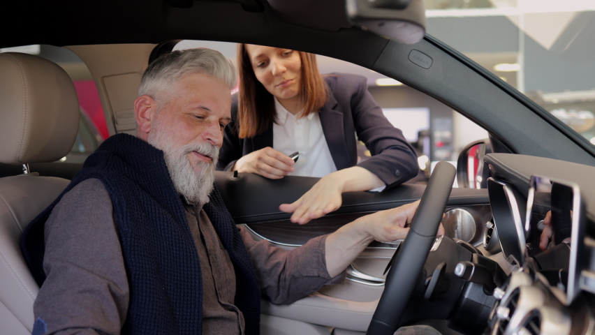 Sales manager car agent tell old man client about detail quality as he sit on seat in new auto  Royalty-Free Stock Footage #1075148837