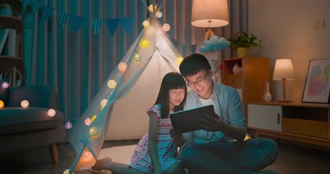 asian girl and her father enjoy their fun time with digital tablet in the evening at home