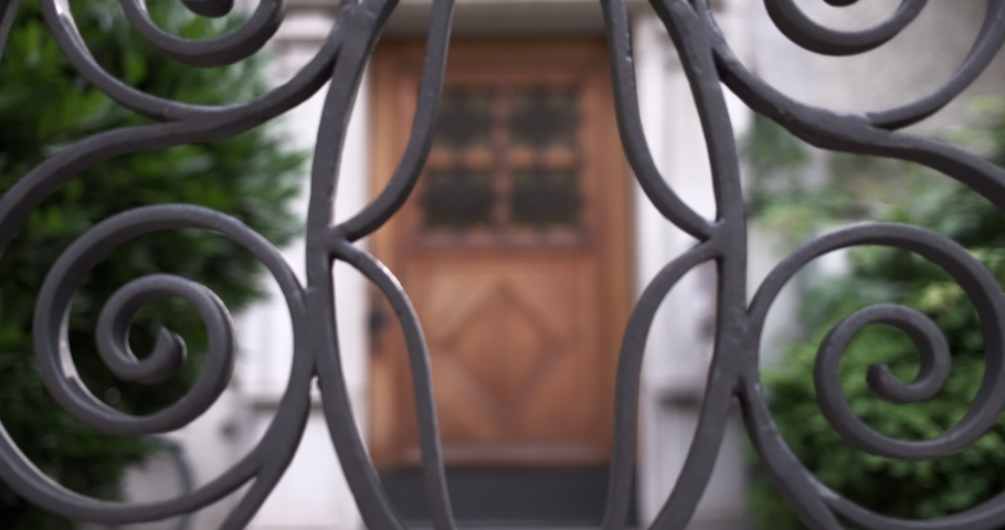 Steady shot with pulling focus through a metal fence against the door of an old apartment building in Zurich, Switzerland