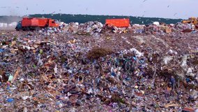 The landfill is located next to the forest. Orange garbage trucks unload garbage. Household waste management industry. Utilities. High quality. 4k footage. - Powered by Shutterstock - Get 15% off with code: PIKWIZARD15