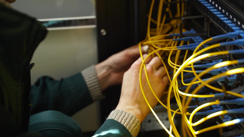 Worker connects optical line internet wire in connection box. Service man soldering optical fiber. Internet service provider engineer working in server room with the optic fiber and router wiring. Royalty-Free Stock Footage #1075173770