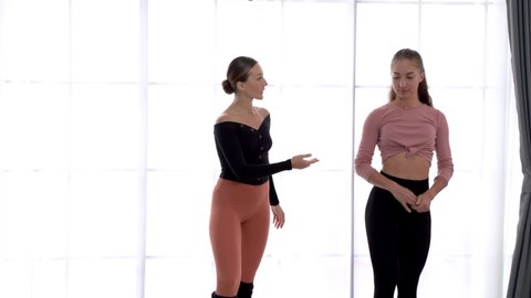 Beautiful woman learning dancing ballet pose with female instructor in performance dance studio. warm up exercise activity, gymnastics or ballet dancing class, or healthy people lifestyle concept.