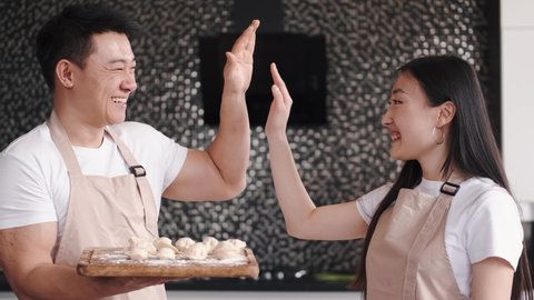 Portrait of happy young Asian couple cooking together in the kitchen at home