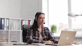 Girl internet teacher doing distant chat working. Close up. Smilimg young business female wears headset talks to web camera making distance online video conference call in office. Job interview.