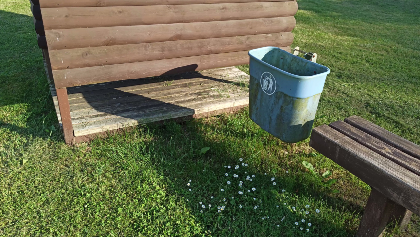 Sign: Throw away the trash. Trash can outside on the grass. Eco content. Clean area.