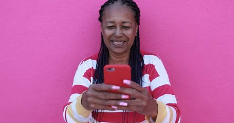 Senior african woman using smartphone app - Joyful elderly black person enjoy technology