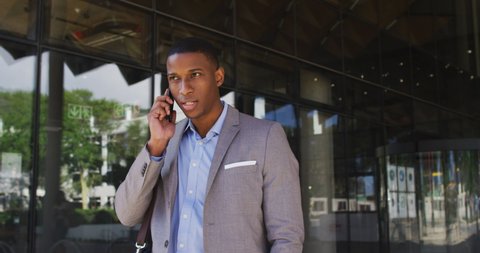 African american businessman talking on smartphone outside of modern office building. business and business people in office concept.