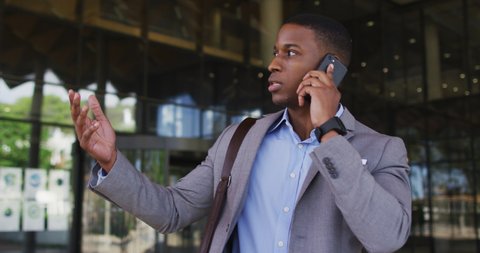 African american businessman talking on smartphone outside of modern office building. business and business people in office concept.