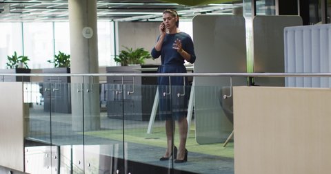 Caucasian businesswoman talking on smartphone in corridor in modern office. business and business people in office concept.