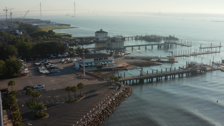 Charleston aerial of yacht club in South Carolina. Moody morning shot with Arthur Ravenel Bridge in distance. Cruise ships dock at harbor where slaves were once traded in historic colonial America.