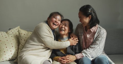 Smiling senior asian woman with adult daughter and granddaughter embracing. multi generation family, senior lifestyle, togetherness and happiness concept.