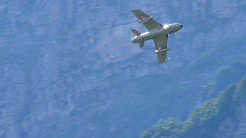 Mollis Switzerland AUGUST, 16, 2019 1950s single-engine jet warplane with arrow wing in low and fast flight in an alpine valley. Hawker Hunter two seats transonic fighter aircraft of Swiss Air Force