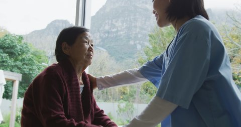 Smiling asian female doctor comforting senior female patient and talking at surgery. physiotherapy, health and healthcare services.