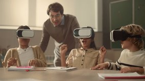 Male teacher and children in vr glasses learning cyber space in classroom. Diversity pupils wearing virtual reality headsets. Excited boys and girls in virtual glasses having fun at lesson in school - Powered by Shutterstock - Get 15% off with code: PIKWIZARD15