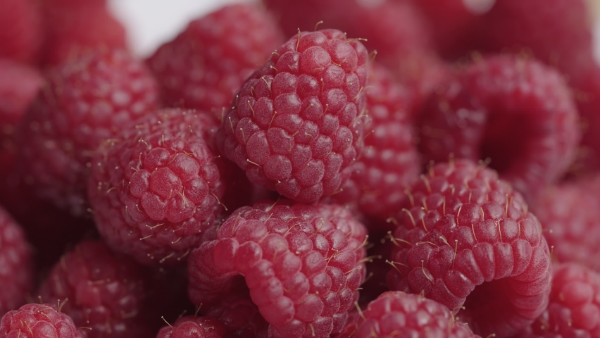 Pouring juicy fresh raspberries into cream or yoghurt. Sweet red berries covered with a white milky liquid. Vitamin healthy dessert. Beautiful background of appetizing food. Close up. Slow motion.