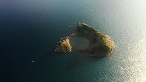 Drone flying over green Islet of Vila Franca do Campo in sunset light, Sao Miguel Island, Azores, Portugal, Europe. Overhead shot of volcanic islet washing by atlantic ocean water, 4k footage
