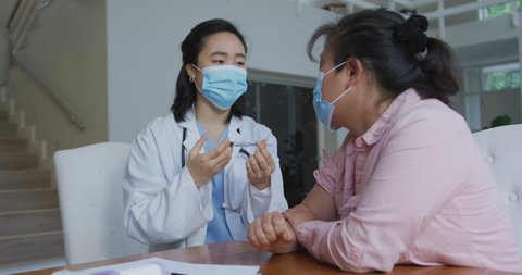 Asian female nurse wearing face mask preparing covid vaccination for female patient in hospital. medicine, health and healthcare services during coronavirus covid 19 pandemic.