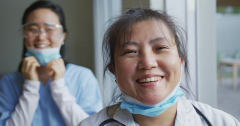 Portrait of asian female nurse and patient wearing face masks, lowering masks and smiling to camera. medicine, health and healthcare services during coronavirus covid 19 pandemic.